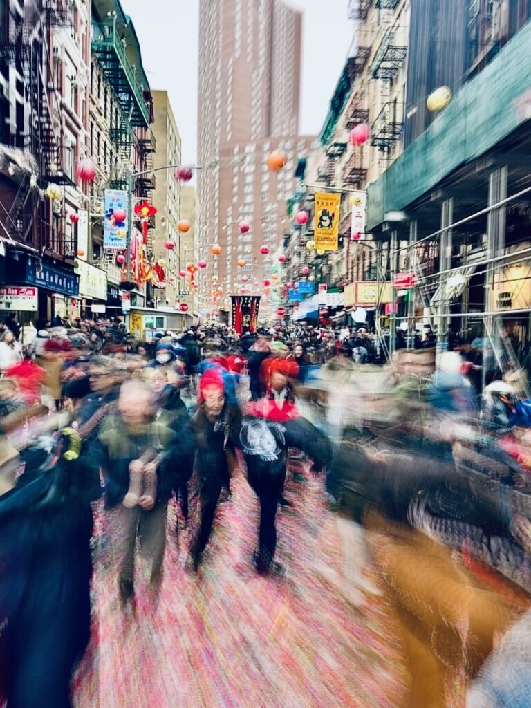 Two people walking down a busy city street in a vibrant Chinatown
